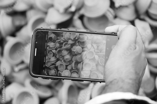 Photography Black and White image of Man taking photos of clay lamps (Diya) with his phone a