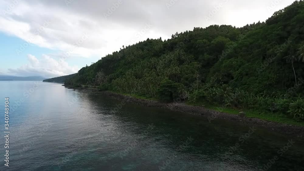 Drone slide on the side of a tropical island. Calm waters, beautiful beach and palm trees. Limasawa Island, Southern Leyte, Philippines. Drone slide on the side of a tropical island. Calm waters, beautiful beach and palm trees. Limasawa Island, Southern Leyte, Philippines.