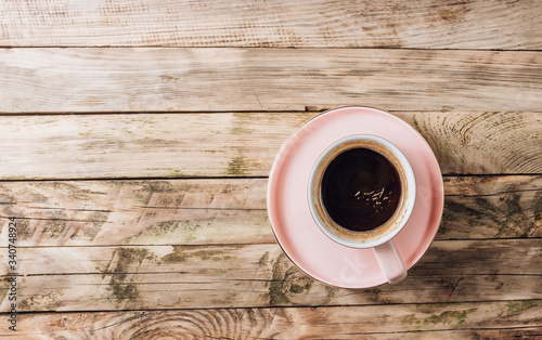 A pink cup of fresh coffee on a rustic wooden background. Minimal concept. Top view
