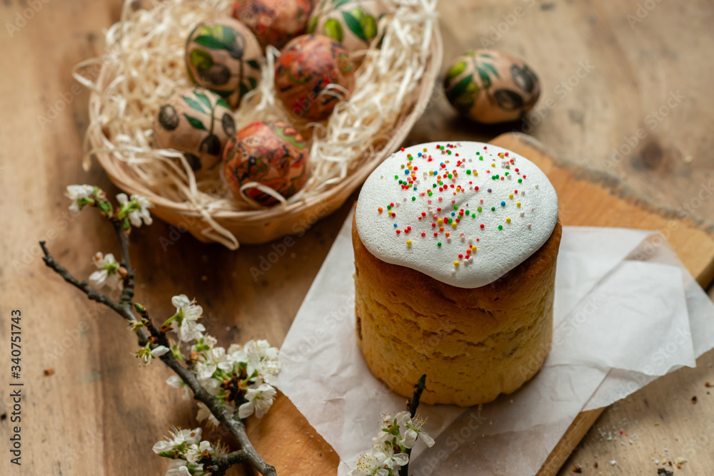 Easter cake, and Easter eggs in a wicker basket with a flowering branch on a wooden background Easter cake, and Easter eggs in a wicker basket with a flowering branch on a wooden background