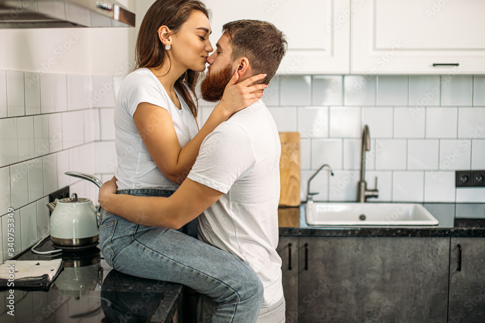 lovely caucasian couple kissing and hugging each other in the kitchen at home. sexy sensual couple in love. indoors, isolated in modern stylish kitchen lovely caucasian couple kissing and hugging each other in the kitchen at home. sexy sensual couple in love. indoors, isolated in modern stylish kitchen