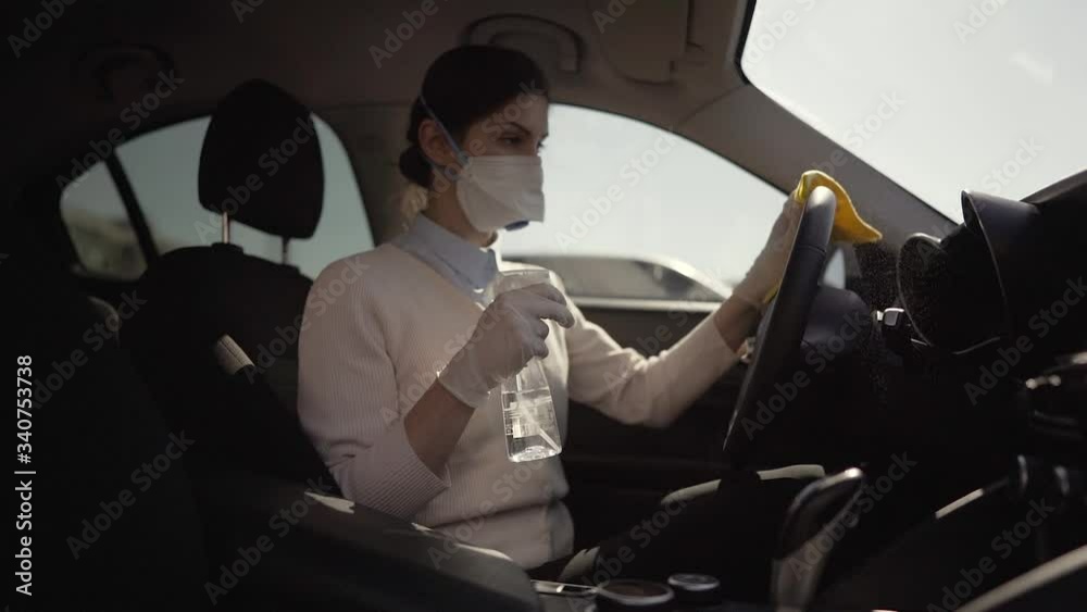 Car owner disinfecting vehicle with alcohol based sanitizing solution spray.Touched surfaces sanitation.Coronavirus COVID-19 spread prevention.Cross-contamination.Steering wheel disinfection