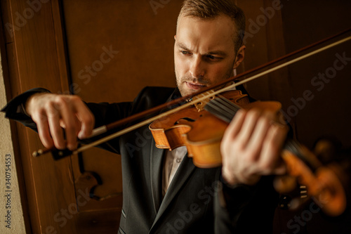 handsome caucasian guy with classic instrument violin, talented male musician in theatre practice before performance