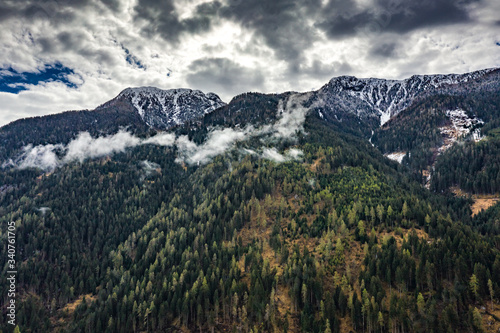 Aerial view of valley with green slopes of the mountains of Italy, Trentino, The trees tumbled down by a wind, huge clouds over a valley, green meadows, Dolomites on background, cloudy weather