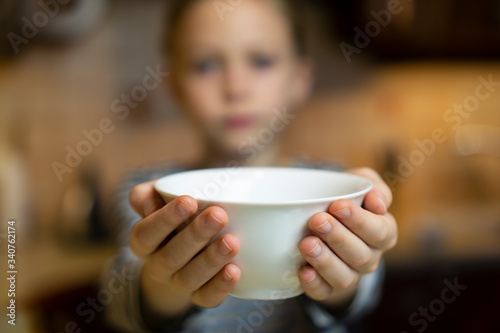 Obraz na plátně Child reaching out hands holding white empty bowl plate offering food or asking