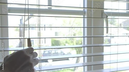 A man opening venetian blinds