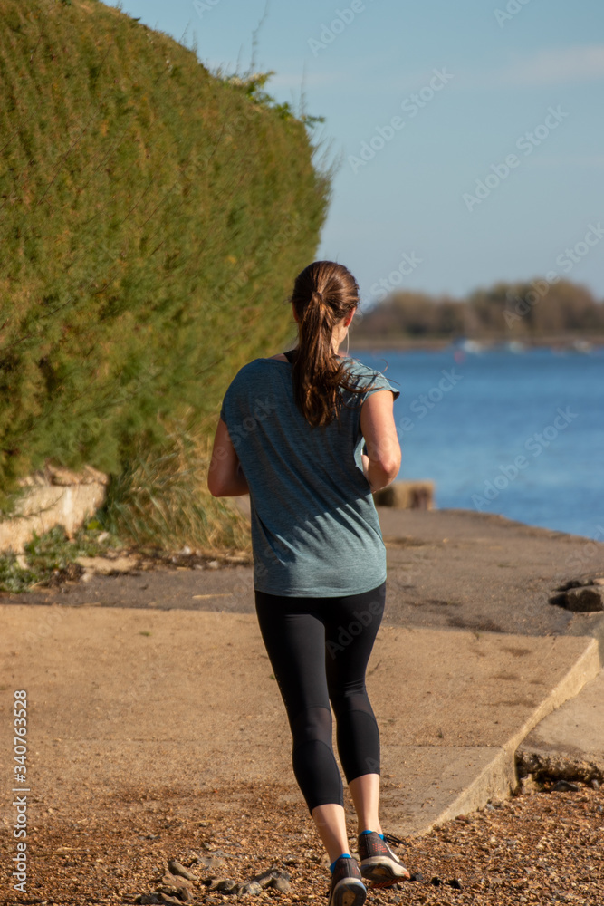 A young woman jogging alone along the shore side A young woman jogging alone along the shore side
