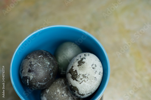 Blue plate bowl with marble pastel coloured Easter eggs table top view close-up with space