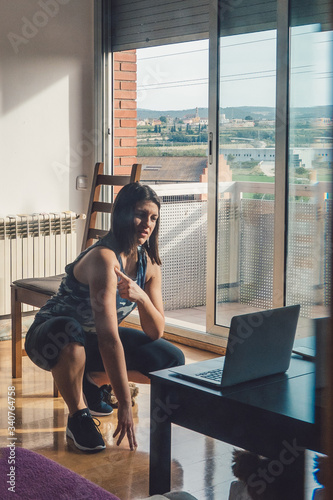 girl in her living room talking to her personal trainer through a video call photo