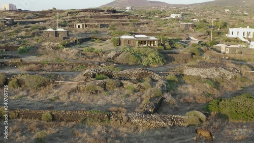 The sea of ​​Pantelleria with its jagged and volcanic coast. Turquoise colored sea. Dammusi, typical houses of Pantelleria.
