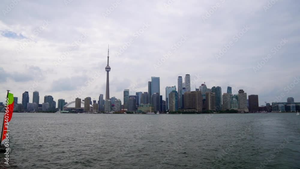Sailboat floats by as Toronto Island Ferry drifts away from downtown waterfront skyline Sailboat floats by as Toronto Island Ferry drifts away from downtown waterfront skyline