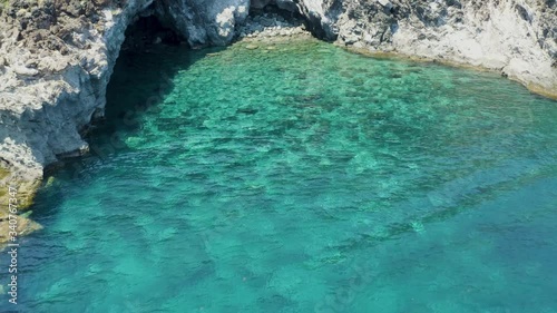 The sea of ​​Pantelleria with its jagged and volcanic coast. Turquoise colored sea. Dammusi, typical houses of Pantelleria.