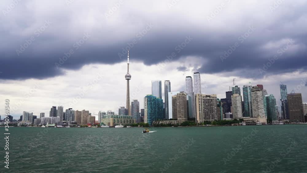 Slow motion water taxi boat on Lake Ontario with downtown Toronto waterfront buildings and stormy clouds Slow motion water taxi boat on Lake Ontario with downtown Toronto waterfront buildings and stormy clouds