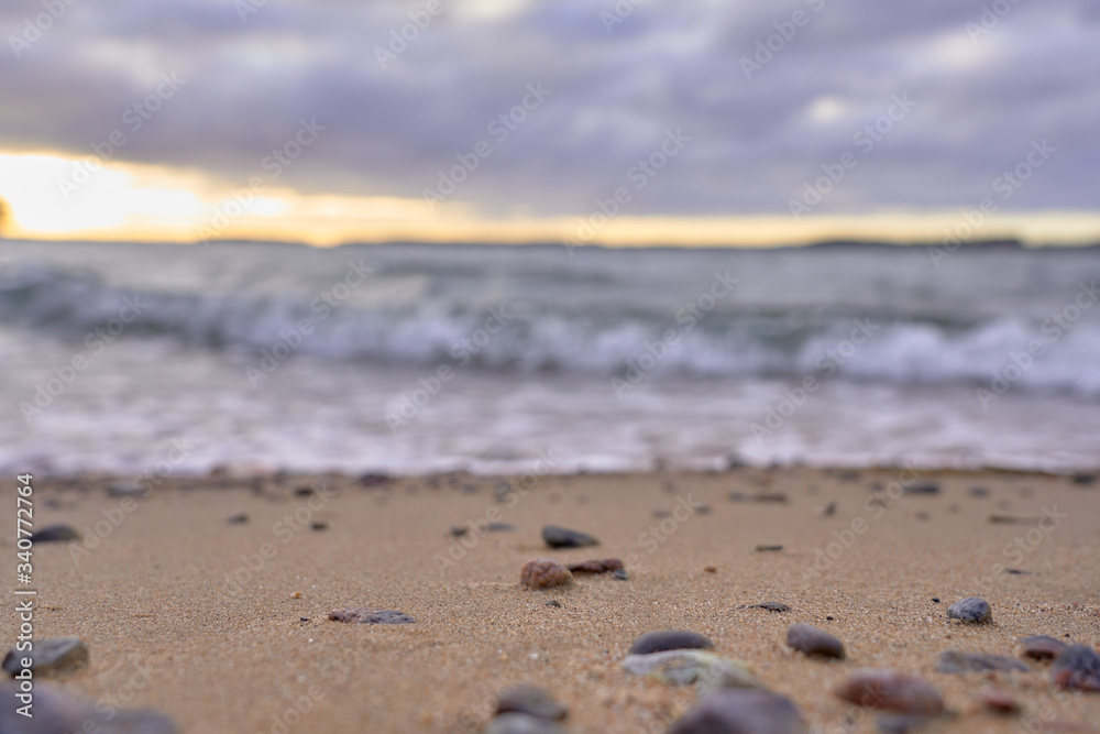 Blurred sandy beach with stones and waves on a background on a sunset. Blurred sandy beach with stones and waves on a background on a sunset.