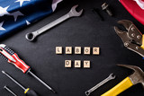 Happy Labor day concept. American flag with different construction tools on black table background, with Labor Day text.