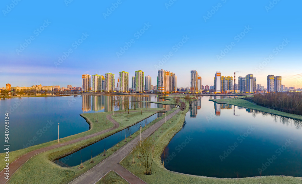 Fototapeta premium Residential complex on the shore of the lake. Modern urban architecture. Apartments in new buildings near the recreation area. Urban landscape. Ponds and houses under a blue sky.
