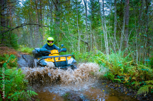 A man rushes on an ATV on a forest road. Yellow ATV drives throu