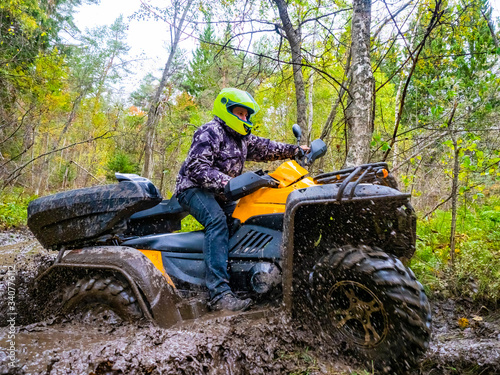 A man rides a ATV on a dirt road. Rider on a Quad bike in a pudd