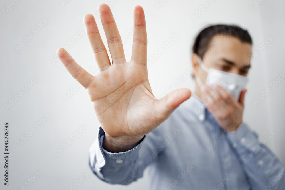 man in a protective mask shows a hand stop sign to stop the outbreak of the coronavirus epidemic man in a protective mask shows a hand stop sign to stop the outbreak of the coronavirus epidemic
