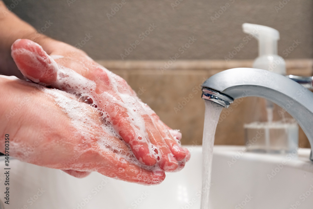 Fototapeta premium Washing hands with soap and water in bathroom sink, protection against covid-19 coronavirus flu viruses, hygiene to stay healthy