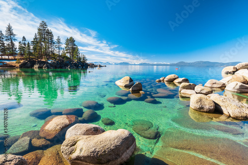 Lake Tahoe rocky shoreline in sunny day, beach with blue sky over clear transparent water photo