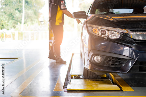 car automobile mechanic working on repairing the wheel tire of vehicle, taking car in for service workshop for male car mechanic fixing problems replacing broken parts of using tools and equipment