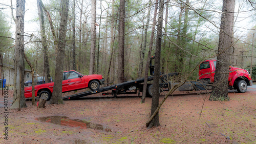 Fotografia Red pickup truck being loaded on red tilt bed tow truck to be hauled away