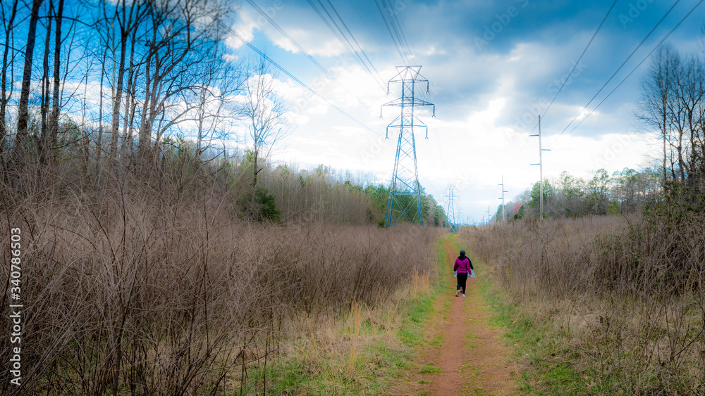 Women walking along path next to power lines with storm clouds in the background Women walking along path next to power lines with storm clouds in the background