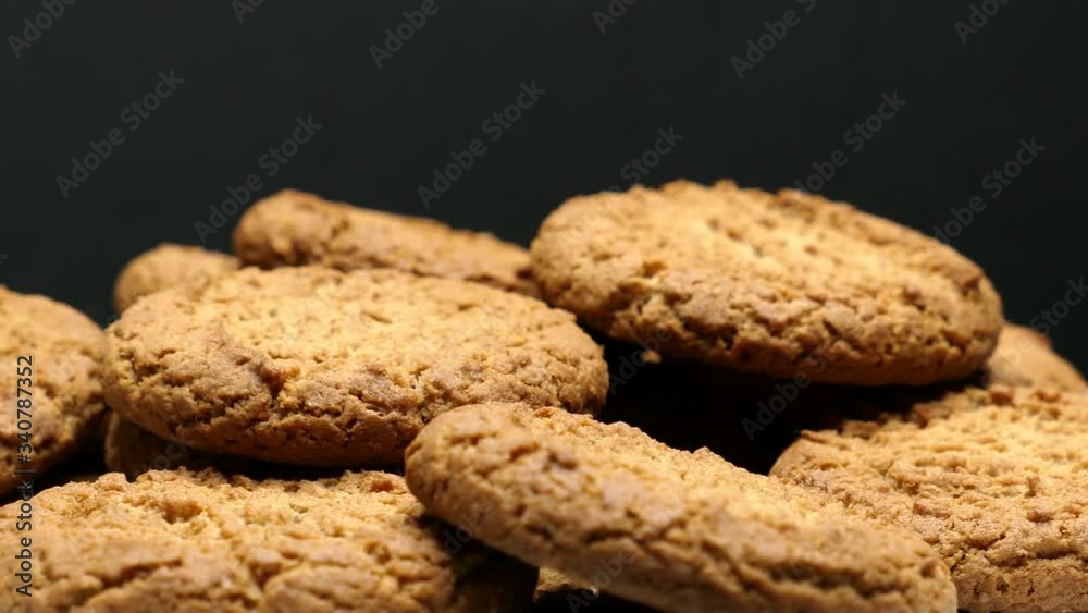 Rotating Close Up Of Fresh Brown Oatmeal Cookies On A White Plate On A Black Background. Rotating Close Up Of Fresh Brown Oatmeal Cookies On A White Plate On A Black Background.