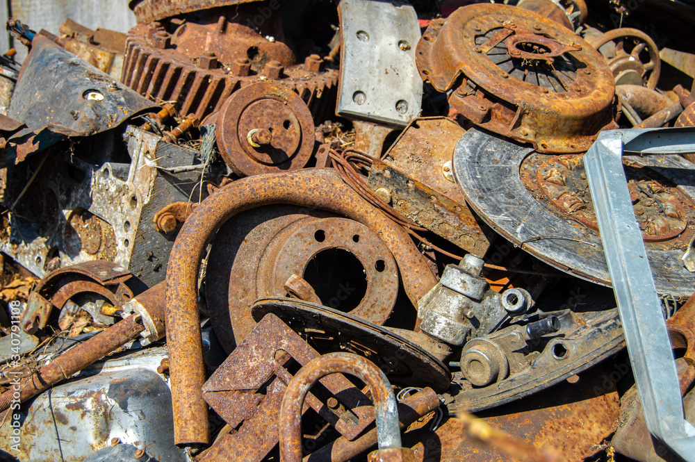 A pile of rusty scrap metal from cars in the sunlight