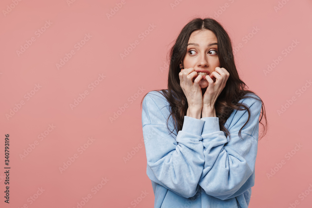 Image of scared brunette woman frowning and biting her nails Image of scared brunette woman frowning and biting her nails