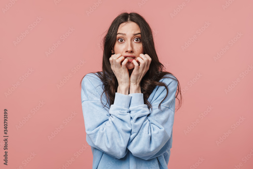 Image of scared brunette woman frowning and biting her nails Image of scared brunette woman frowning and biting her nails