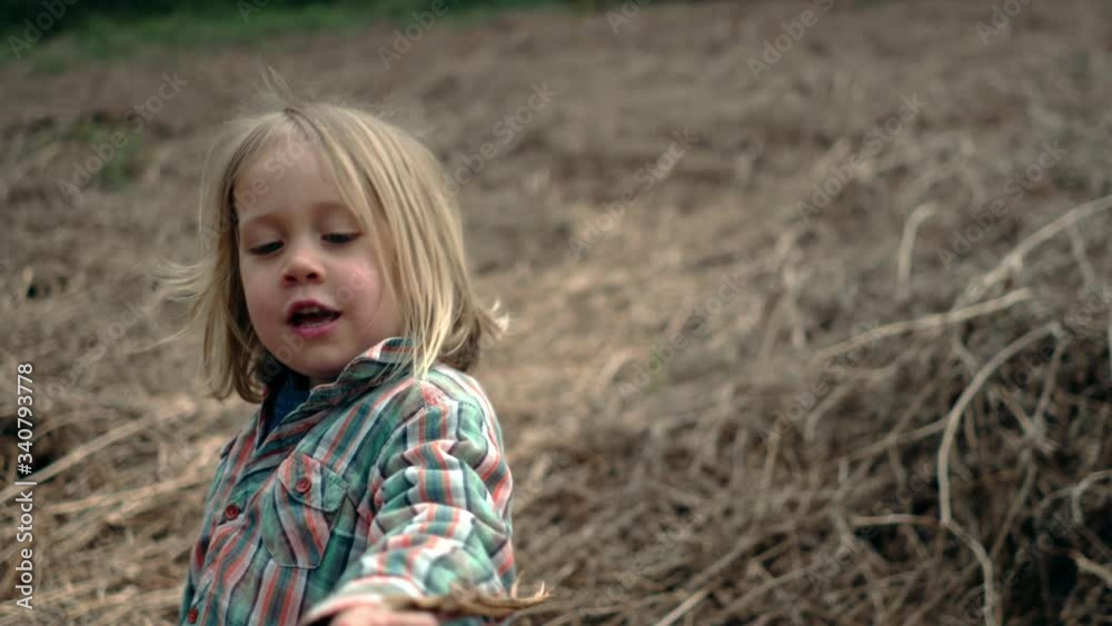 Preschooler standing in field with a stick in his hand Preschooler standing in field with a stick in his hand