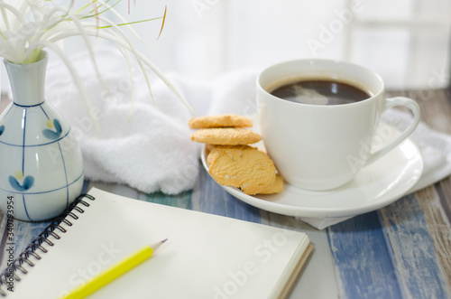 Cup of hot coffee with .butter cookies,  notebook and flower on a wooden table holiday home vacation ideas
