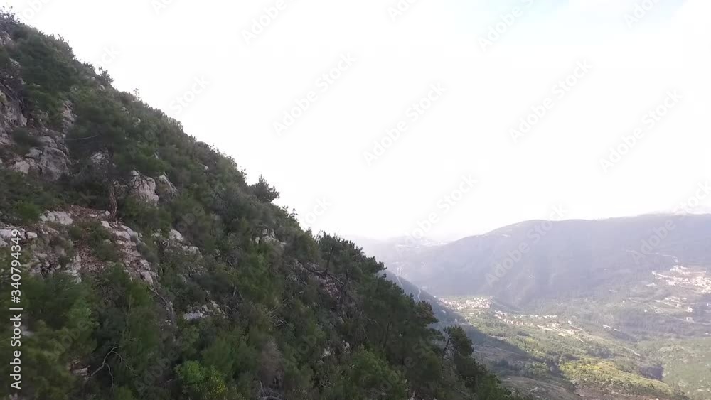 Dramatic aerial flight towards and past the side of rocky cliffside to reveal mountain range Dramatic aerial flight towards and past the side of rocky cliffside to reveal mountain range