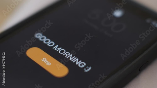 Good morning alarm clock on the phone , close-up. Hand tapping stop.