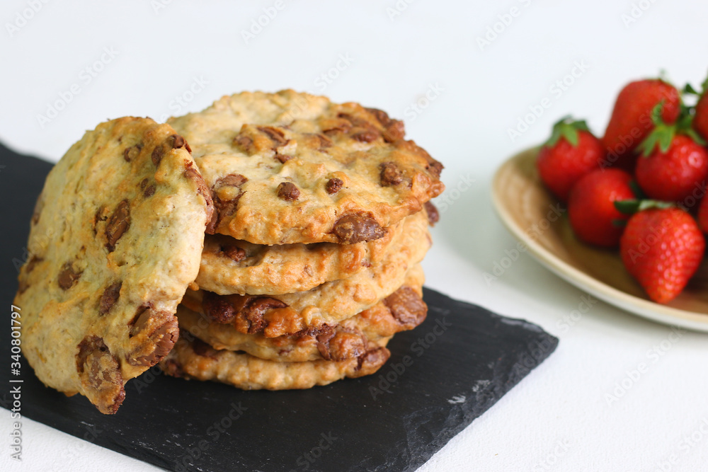 cookie with chocolate on plate and strawberry on light background.