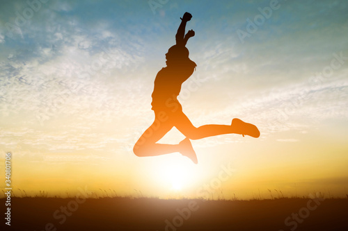 Silhouette of happy people young woman jumping sunset.
