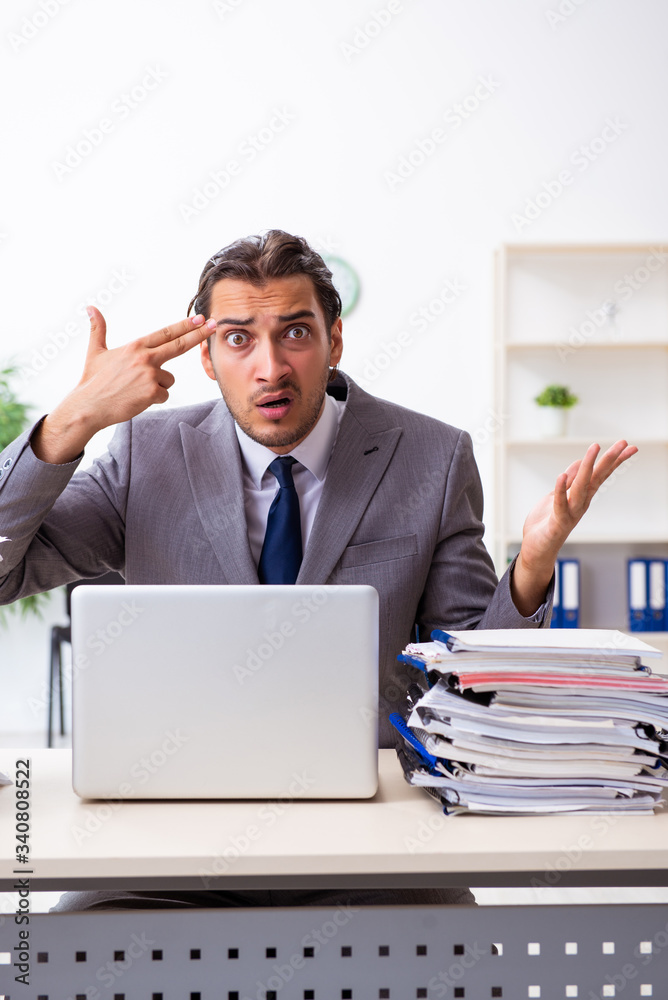 Young male employee unhappy with excessive work Young male employee unhappy with excessive work