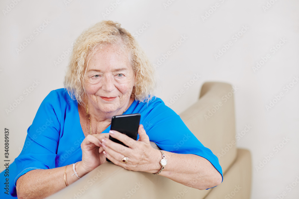 Smiling elderly woman checking text messages and notifications on her smartphone Smiling elderly woman checking text messages and notifications on her smartphone