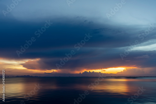 Sunset sky at the lake with rain cloud and light in golden hour. © noppharat