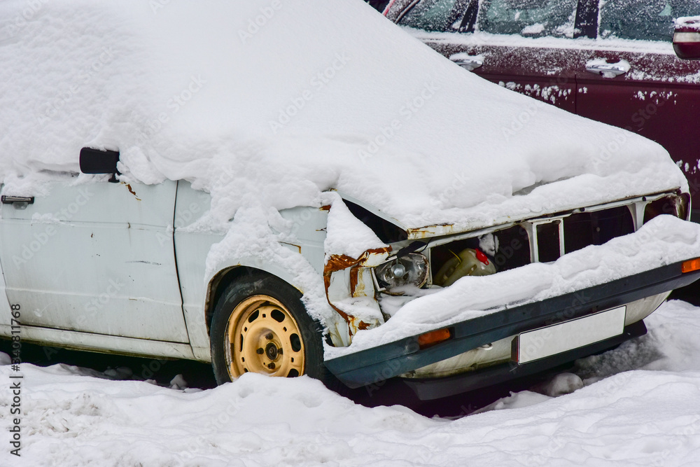 Fragment of a white broken car covered with snow close-up