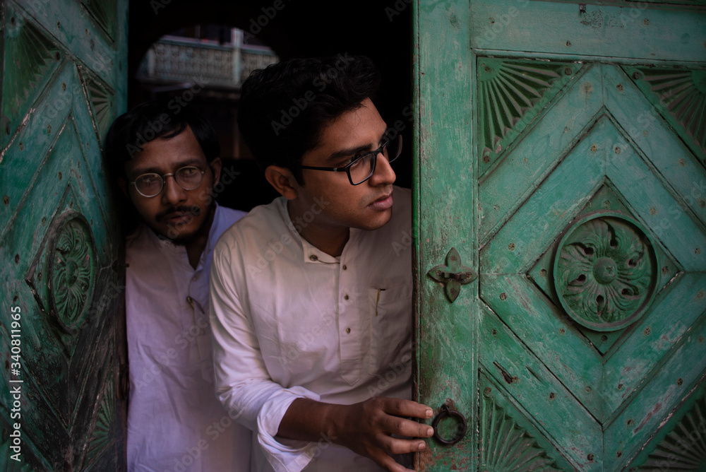 Young Indian Bengali detective and his colleague with traditional wear entering an old house. Indian lifestyle.