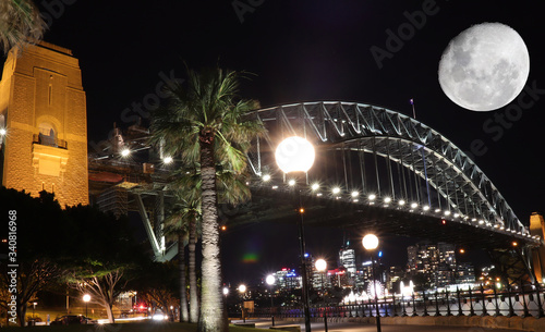 Sydney harbour illuminated by the moon and circular quay with vibrant colourful lights at midnight in NSW Australia