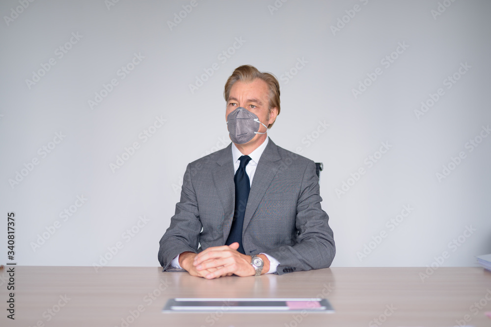 Mature businessman working with mask for protection from corona virus outbreak at work Mature businessman working with mask for protection from corona virus outbreak at work