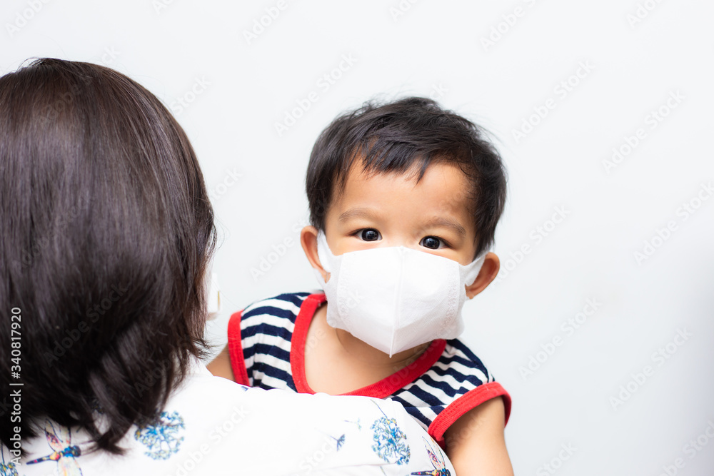 Asian mother holding her son wearing protective mask against covid 19 virus and PM 2.5 air pollution Asian mother holding her son wearing protective mask against covid 19 virus and PM 2.5 air pollution