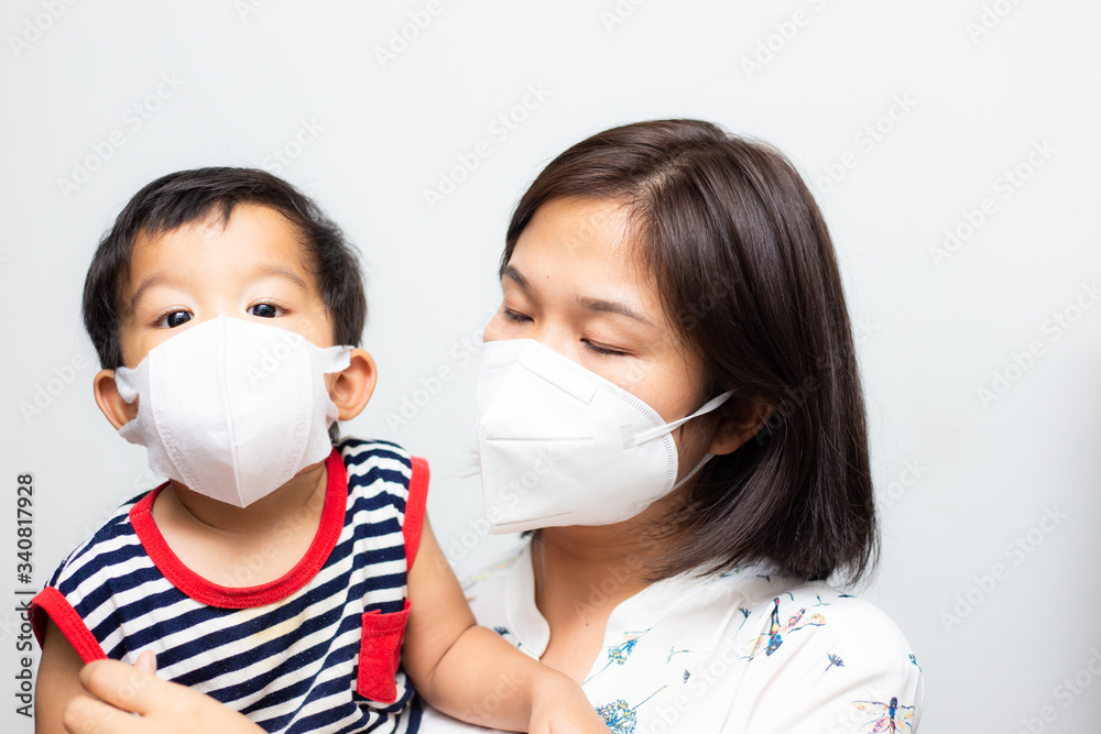 Asian mother holding her son wearing protective mask against covid 19 virus and PM 2.5 air pollution