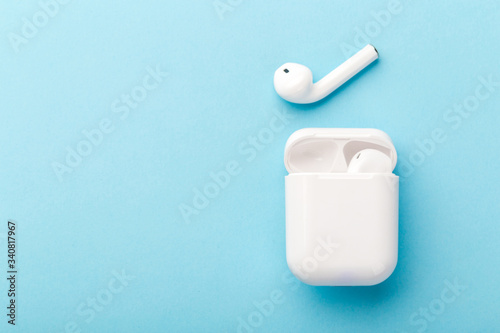 Modern wireless bluetooth headphones with charging case on a blue background.
