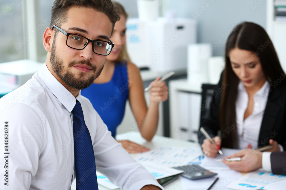 Handsome smiling bearded clerk man wearing glasses look in camera office portrait group of colleagues in background. Human resource modern training course strategy consult concept Handsome smiling bearded clerk man wearing glasses look in camera office portrait group of colleagues in background. Human resource modern training course strategy consult concept