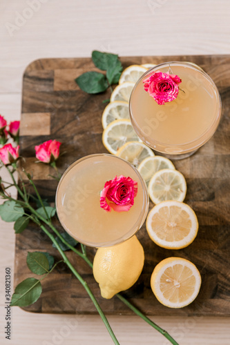 Two alcoholic beverages garnished with flowers and lemons in a pretty glassware